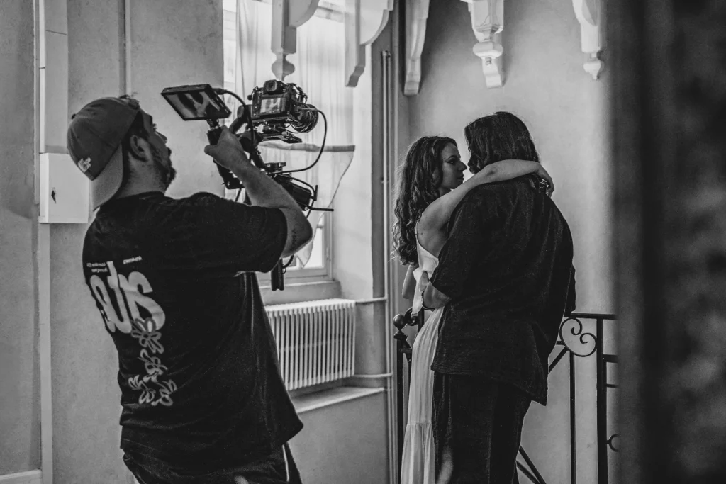 Tournage d'un clip vidéo professionnel avec un caméraman filmant une scène émouvante entre deux acteurs.